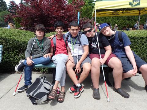 Gabe, Saifullah, Octavio, Isaiah and Henry sitting on bench at Garden Party smiling