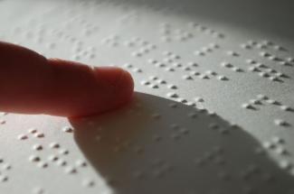 A finger moving over a sheet of braille