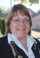 Jennifer’s headshot taken on a sunny morning with an excited smile wearing a black/white suit and a shimmery musical broach.