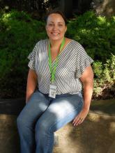 Melissa Lile with brown hair pulled back on face, smiling in front of a rhododendron at WSSB.